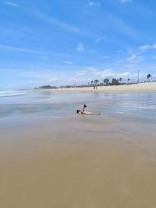 eine Person, die am Strand im Wasser liegt in der Unterkunft Sol e mar in Fortaleza