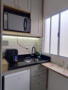 a kitchen with a sink and a microwave at Lofts Baronesa in São José dos Campos