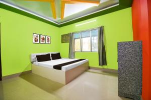 JalpāiguriにあるHotel O Shiv Shakti Homestayの緑のベッドルーム(ベッド1台、窓付)