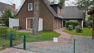 a house with a fence in front of a tree at Haushaelfte-Hein-105 in Böhl