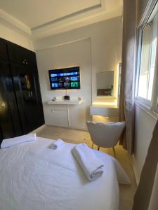 マラケシュにあるHomesweethomeのベッドと椅子とテレビのある寝室