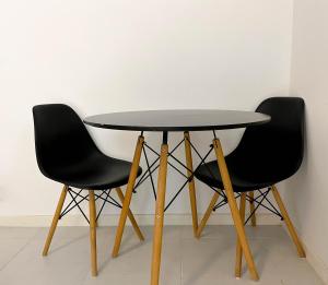 two black chairs around a round table with a table at Flat particular no hotel Fusion in Brasilia