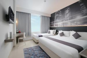 a hotel room with two beds and a desk at Hotel Neo Candi Simpang Lima - Semarang by ASTON in Semarang +29 photos