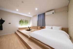 水原市GOYU Hotel的卧室里有一张白色的大床和一张桌子