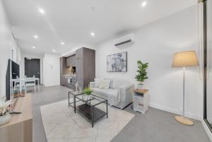 メルボルンにあるLuxurious 2BR Apartment - Central CBD Location with Pool, Gymの白いソファとテーブルのあるリビングルーム