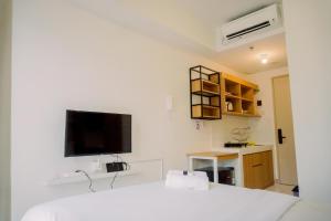 a bedroom with a bed and a tv on the wall at Relaxing Designed Studio at Tokyo Riverside PIK 2 Apartment By Travelio in Rawalembang