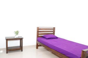 a bed with purple sheets and a night stand next to a table at Jana Safari Hostel Udawalawe in Udawalawe +9 photos