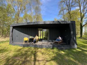 two people sitting in a black house in a field at Capsula aan de Wadi in Diepenheim +8 photos