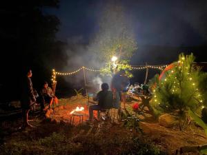 a group of people sitting around a fire at night at BLa Coconut House in Bảo Lâm