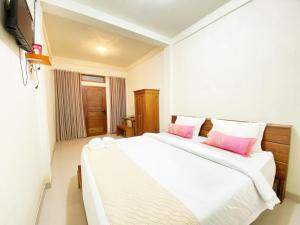 a bedroom with two beds with pink pillows at Bujai Mentawai Griya Hotel in Tuapejat
