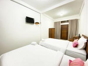 a hotel room with two beds and a mirror at Bujai Mentawai Griya Hotel in Tuapejat