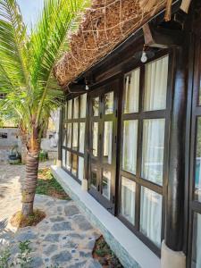 a building with windows and a palm tree in front of it at Bently farm Retreat Mũi Né- Bungalow Family 2 rooms-0506 in Ấp Phú Hiệp