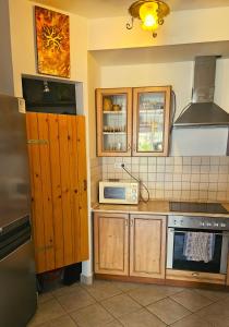 a kitchen with wooden cabinets and a microwave at Koczor Apartman in Balatonfüred