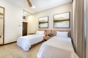 two beds in a hotel room with white sheets at Lush Royale Villa Kotte with Pool & Gym in Sri Jayewardenepura Kotte +59 photos