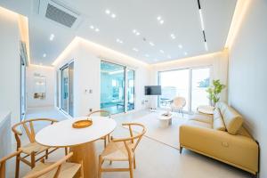 un soggiorno con un divano, un tavolo e delle sedie di Peer Haus Private House a Gangneung