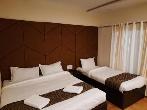 a hotel room with two beds with towels on them at Grandkodai in Kodaikānāl