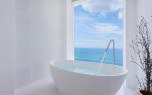a bath tub in a white bathroom with a window at Pohang Escape Ocean View Pool Villa in Hajŏng-ni