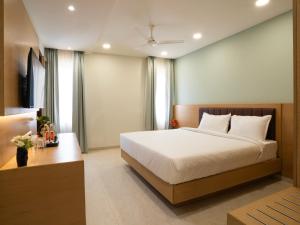 a bedroom with a large white bed and a desk at Hotel Orchid Suites Kokapet, Business Hotel in Hyderabad