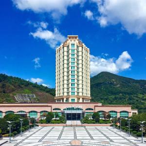 a tall white building with a mountain in the background at The Ocean Resort in Hangho