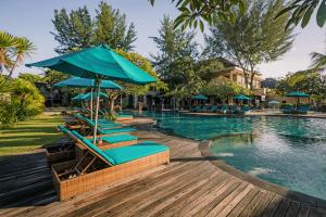 a group of lounge chairs with umbrellas next to a swimming pool at Vila Ombak in Gili Trawangan