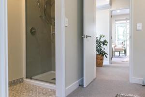 a glass shower door in a hallway with a chair at 3 Bed Family Retreat Classic Charm With Park Views in Christchurch