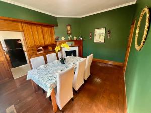 un comedor con una mesa con sillas blancas y paredes verdes en Historic English Manor in New Town, en New Town