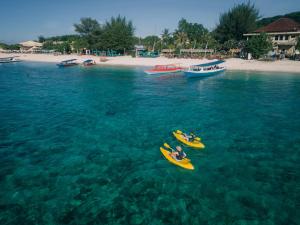 two people in kayaks in the water near a beach at Vila Ombak in Gili Trawangan