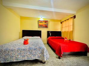 a bedroom with two beds with red comforters at Hotel Emiss Panajachel in Panajachel
