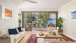a living room with a couch and a tv at Sunset at The Moorings in Soldiers Point