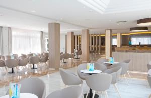 a restaurant with white chairs and tables and a bar at Grupotel Gran Vista & Spa in Can Picafort