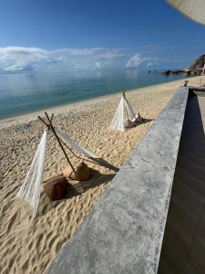 two hammocks on a sandy beach next to the ocean at 4U Resort Samui in Lamai