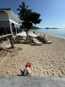 a beach with chairs and umbrellas and a penguin in the sand at 4U Resort Samui in Lamai