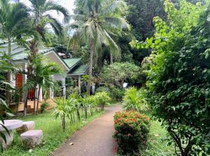 a path leading to a house with palm trees and flowers at 4U Resort Samui in Lamai