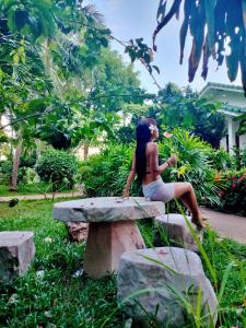 a woman sitting on a stone bench in a park at 4U Resort Samui in Lamai