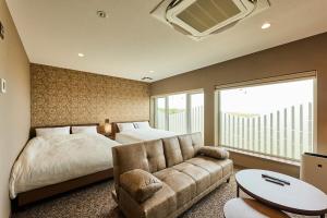 Un dormitorio con una cama, un sofá y un televisor. en Zenibako Sunset, en Otaru
