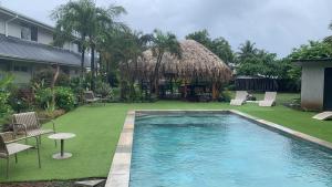 a swimming pool in a yard with chairs and a hut at Tiki Ora Lodge - TIKI in Bora Bora +31 photos