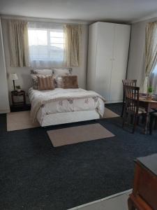 Un dormitorio con una cama y una mesa y sillas. en Cozy, self-catering Garden Flat, en Ciudad del Cabo 7 fotos más