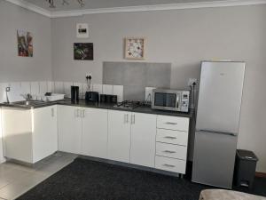 Una cocina con gabinetes blancos y un refrigerador. en Cozy, self-catering Garden Flat, en Ciudad del Cabo