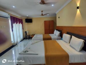 a hotel room with two beds and a television at Hotel Sun World in Kanyakumari