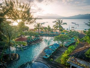 an aerial view of a resort pool with blue umbrellas at Vila Ombak in Gili Trawangan