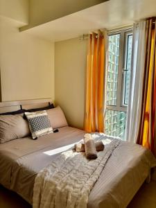 a bedroom with a bed and a window with orange curtains at Pool view Studio with WiFi & Netflix , Avida Riala in Cebu City +32 photos