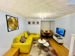a living room with a yellow couch and a table at Chic 2BR escape near Luton Airport&Train Stn, Whipsnade zoo, Contractors in Luton