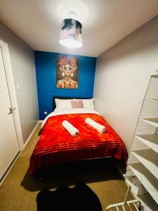 a bedroom with a bed with a red comforter at Chic 2BR escape near Luton Airport&Train Stn, Whipsnade zoo, Contractors in Luton
