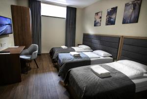 a hotel room with three beds and a desk at Nesvit Hotel in Kyiv