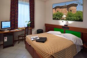 a bedroom with a bed and a desk with a computer at Hotel Il Maglio in Imola