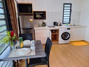 a kitchen with a table with chairs and a washing machine at Papeari sea side 1 Logement neuf en bord de mer in Otutara