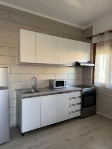 a kitchen with white cabinets and a sink and a refrigerator at Davide's guesthouse in Vlorë