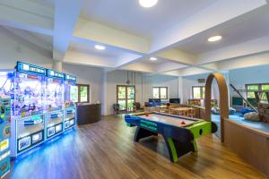 a room with a pool table and a video game at Cape Panwa Hotel Phuket in Panwa Beach
