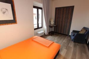 an orange bed in a room with a chair at Il Castello B&B in Varallo Pombia