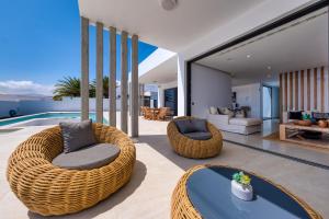 a living room with wicker chairs and a swimming pool at White House - Fire pit and Private pool By Lanzarote Vacation Homes in Puerto Calero